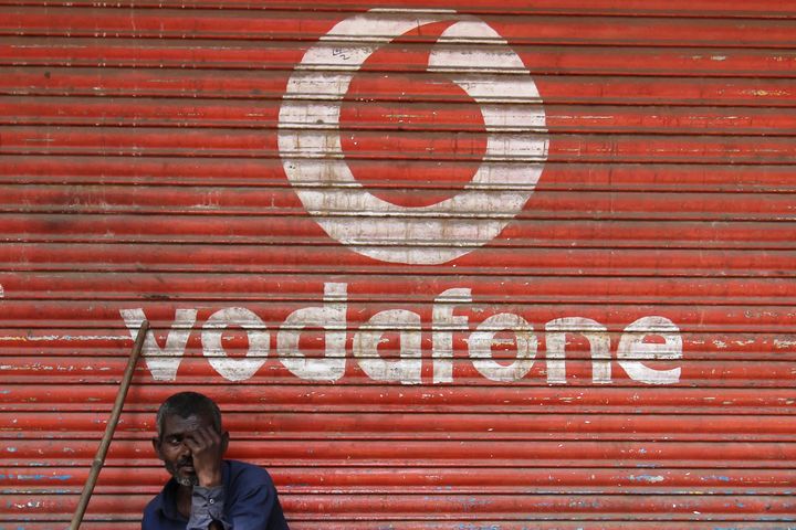 A man sits outside the downed shutters of a shop painted with a logo of Vodafone on its shutter in Mumbai, India on 24 February 2019. India's largest telecom operator Vodafone Idea Ltd has announced the successful consolidation of its radio network integration in Bihar and Jharkhand. Vodafone Idea coverage is now available across 431 Towns and 43503 villages covering 79 percent population as per media report. (Photo by Himanshu Bhatt/NurPhoto via Getty Images)