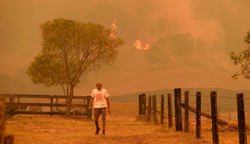 A man walks on a farm as flames approach near the town of Taree, 215 miles north of Sydney, on 14