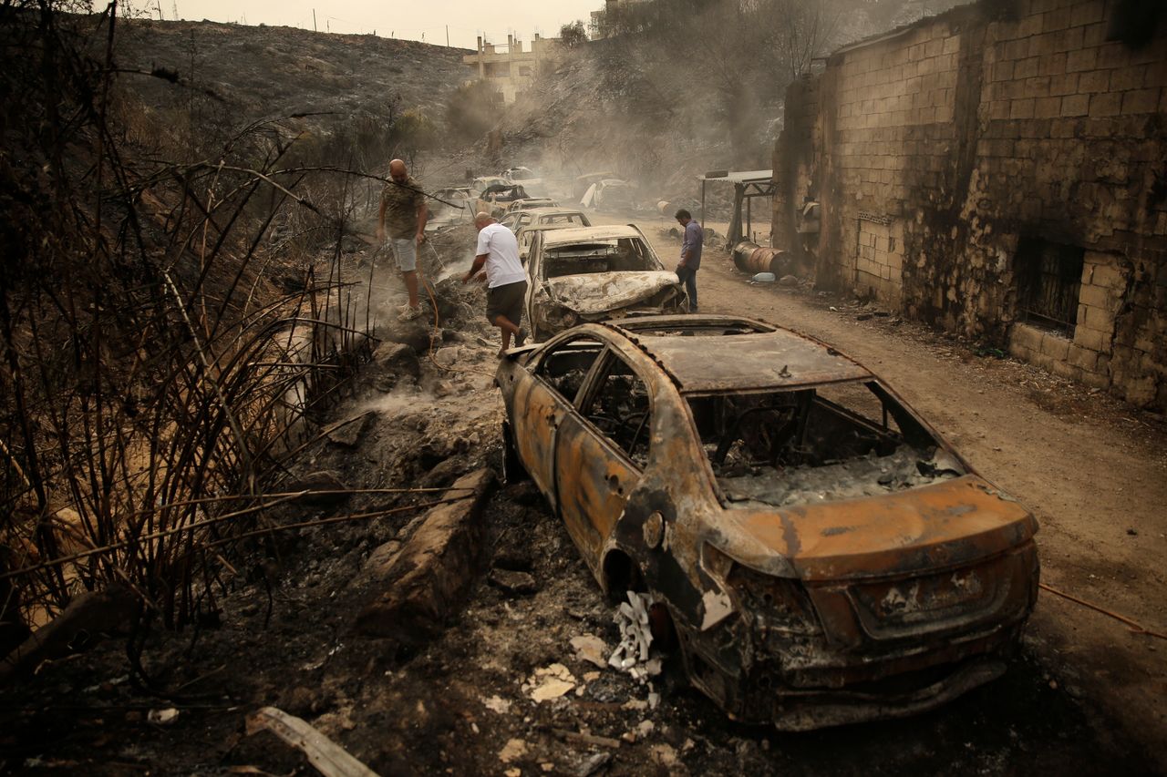 People inspect the remains of cars and shops that were burned in a wildfire in the town of Damour just over 9 miles south of Beirut, Lebanon, on 15 October. Strong fires spread in different parts of Lebanon, forcing some residents to flee their homes in the middle of the night as the flames reached residential areas in villages south of Beirut.