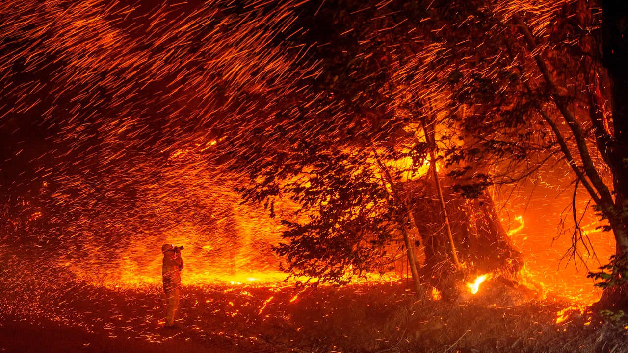 A photographer takes photos amid a shower of embers as wind and flames rip through the area during the Kincade Fire near Geyserville, California, on Oct. 24.