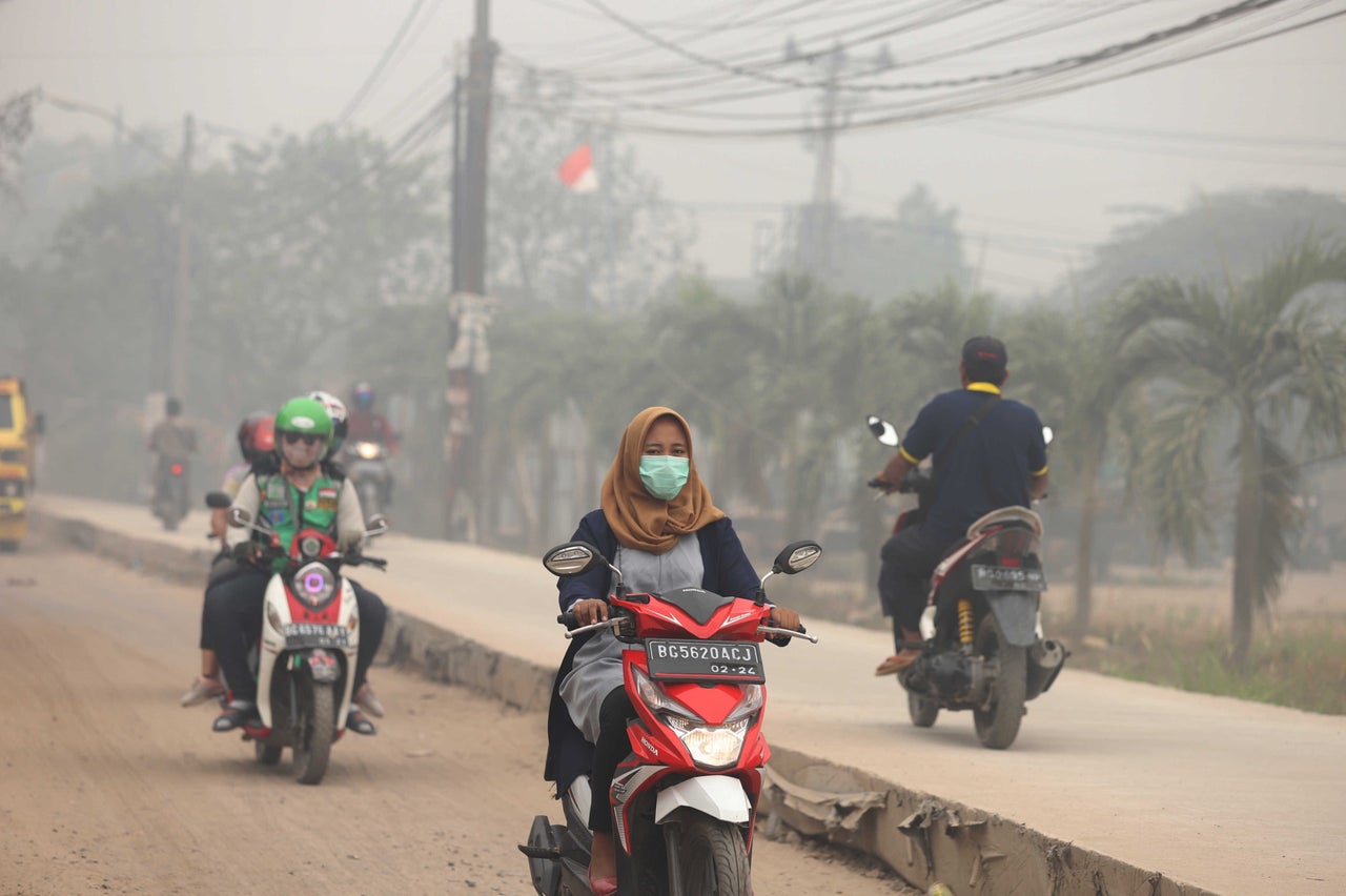 Motorcyclists ride on a road as haze from wildfires blankets the city in Palembang, Indonesia, on Oct. 14. According to the Indonesian Meteorology, Climatology and Geophysics agency, air quality has dropped to dangerous levels.