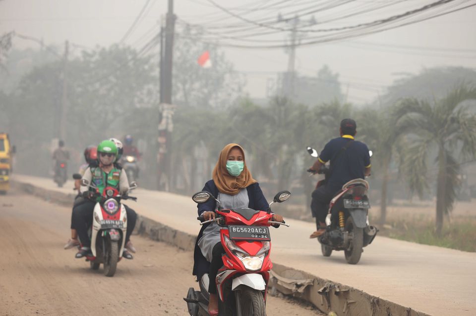 Motorcyclists ride on a road as haze from wildfires blankets the city in Palembang, Indonesia, on 14 October. According to the Indonesian Meteorology, Climatology and Geophysics agency, air quality has dropped to dangerous levels.