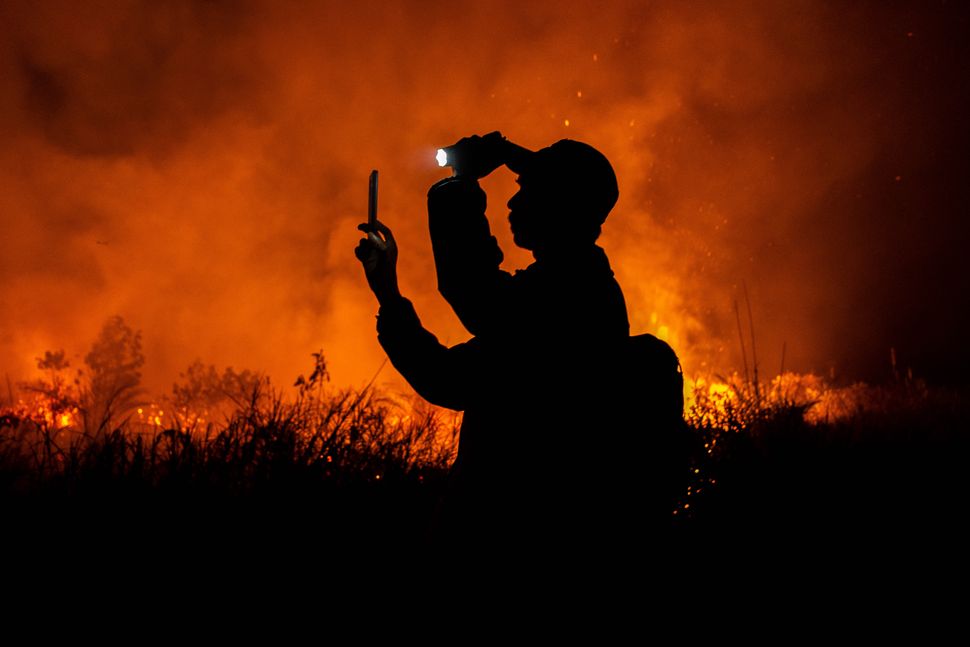 A photographer takes photos of peatland fires in Pekanbaru on 6 October in Riau Province, Indonesia. Slash-and-burn farming practices contributed to the worst blazes since 2015, sickening tens of thousands in Riau.