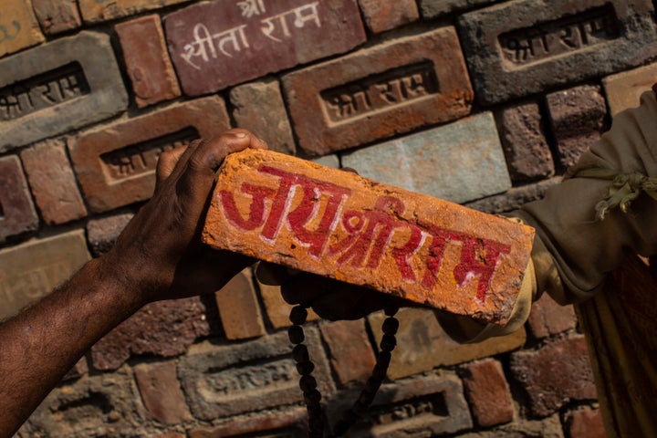 A man holds a brick reading "Jai Shree Ram" as bricks of the old Babri mosque are piled up in Ayodhya. Nov. 25, 2018. 