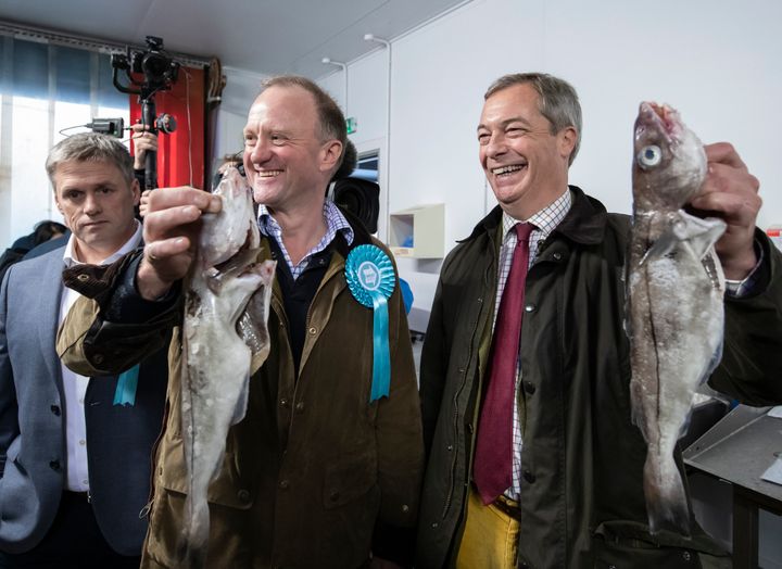 Farage holds a fish with party candidates, Marten Hall, Kingston upon Hull East (left) and Christopher Barker, Great Grimsby constituency, during a stop at the Grimsby Seafood Village