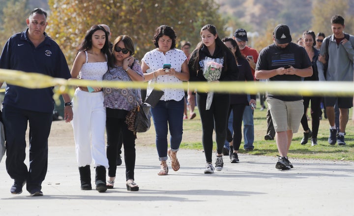 Students and family members walk after being reunited at a park near Saugus High School after a shooting at the school left two students dead.