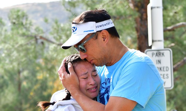 A man embraces his daughter after picking her up at Central Park, after a shooting at Saugus High School.