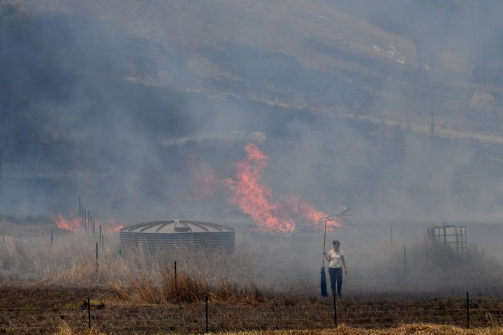 A resident fights a grass fire in the Hillville area near Taree.