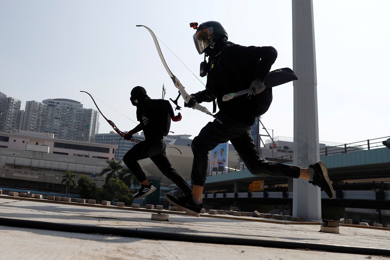 Protesters race with bows as they practice running away from riot police, on the roof of a bus shelter near the Cross Harbour Tunnel, which was blocked after demonstrators occupied the nearby Hong Kong Polytechnic University.
