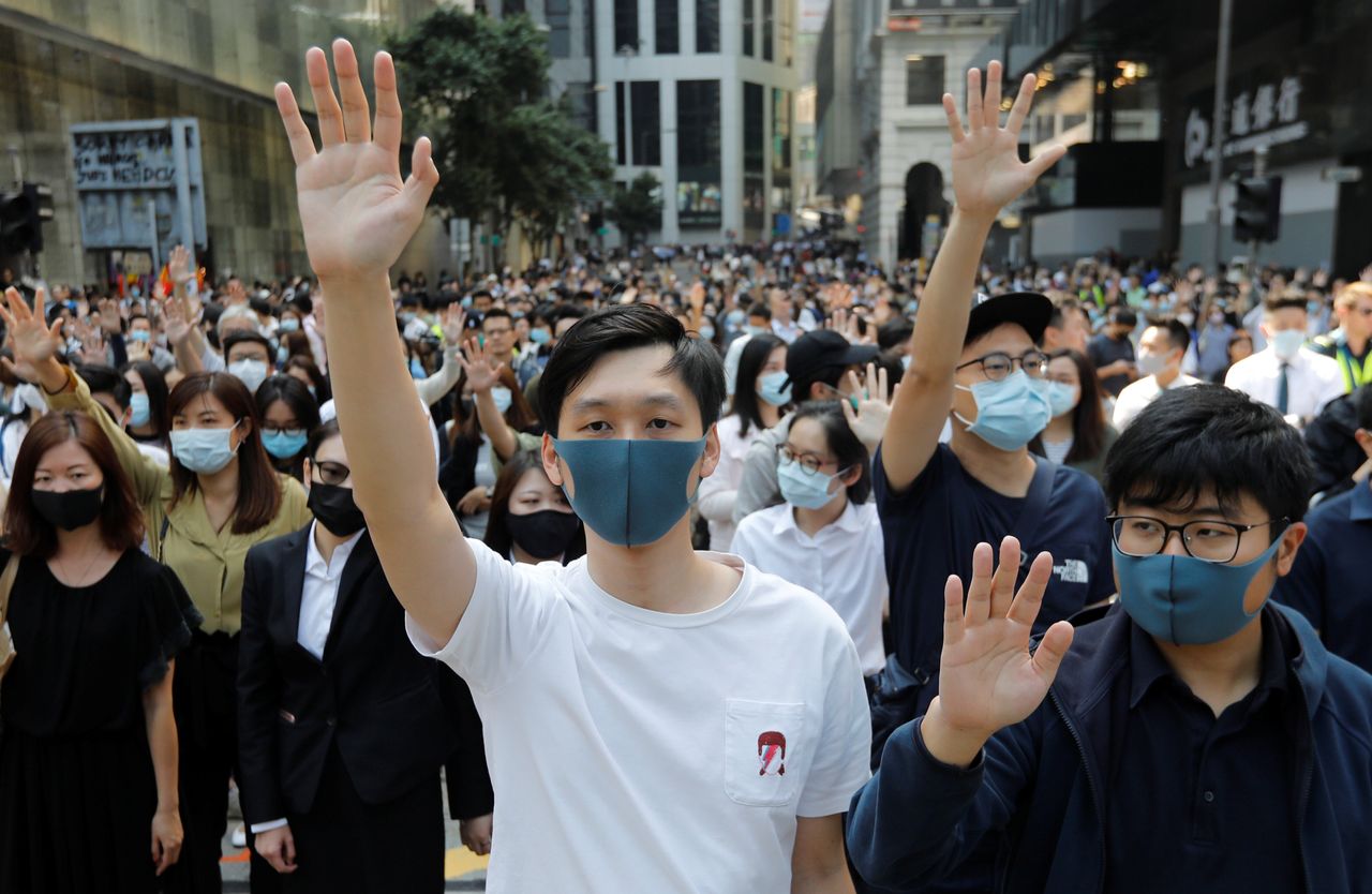 Demonstrators raise their hands as they attend a protest at the Central District on Friday.