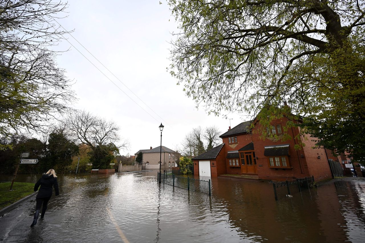 A woman walks through floodwater covering a road near residential properties in Fishlake near Doncaster on Wednesday.
