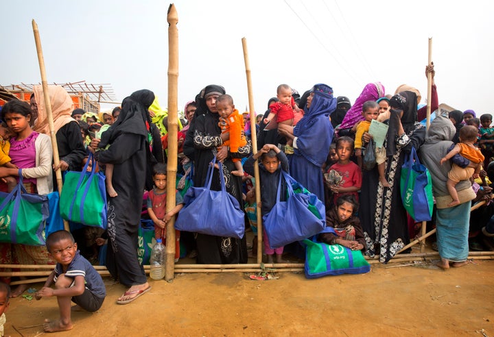 Rohingya Muslim women with their children stand in a queue outside a food distribution center at Balukhali refugee camp in Ba