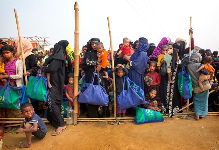 Rohingya Muslim women with their children stand in a queue outside a food distribution center at Balukhali refugee camp in Ba