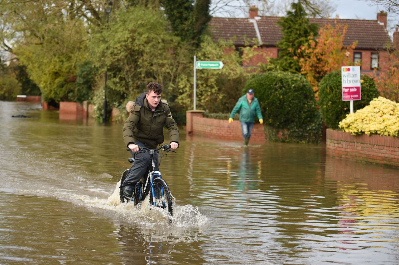 A cyclist navigates a flooded street in the village of Fishlake on Monday.