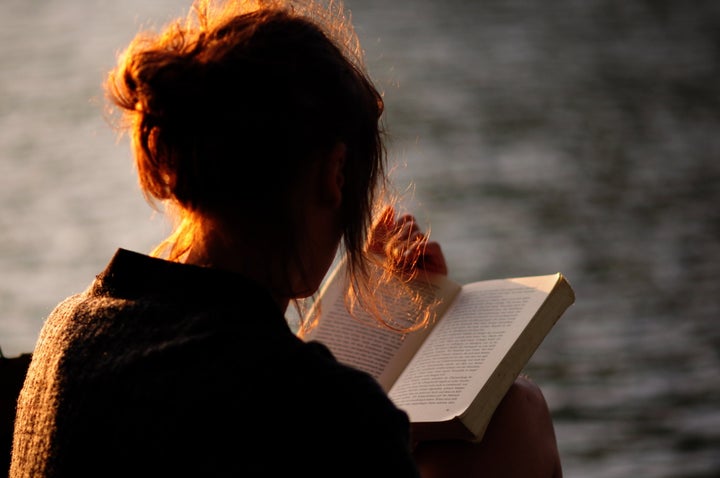 Rear View Of Woman Holding Book Against Lake