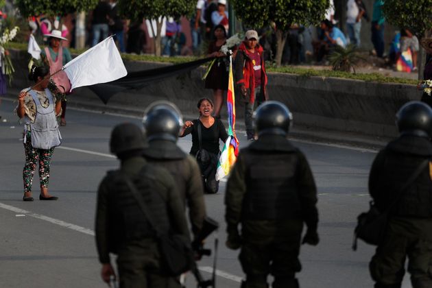 A coca leaf producer kneels leads with police to open the way so a march by backers of former President Evo Morales may continue to Cochabamba, Bolivia, Saturday, Nov. 16, 2019. Officials now say at least eight people died when Bolivian security forces fired on Morales supporters the day before, in Sacaba. The U.N. human rights chief says she's worried that Bolivia could 