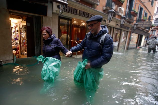 A couple wades their way through water in Venice, Italy, on Friday.