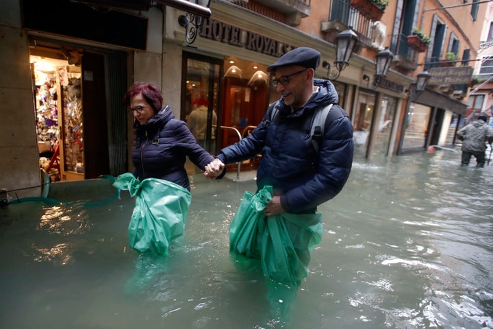 A couple wades their way through water in Venice, Italy, on Nov. 15, 2019. 