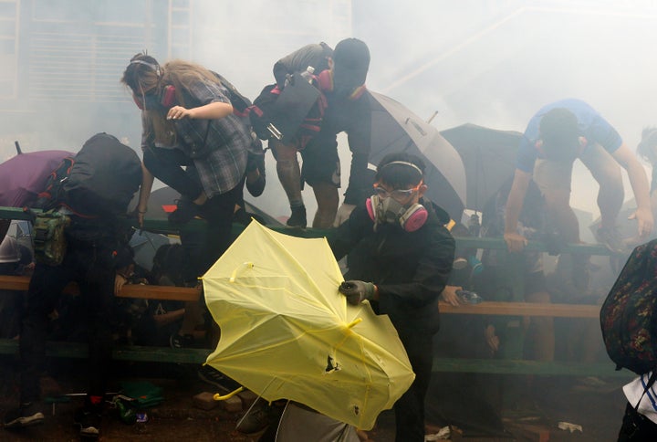 Protesters, some of whom stand behind the umbrellas which have become a symbol of the protest, attempt to escape the campus.