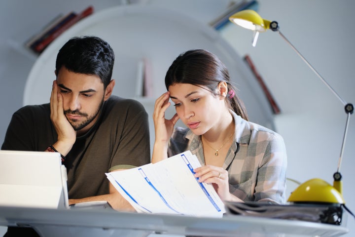 Young couple reviewing invoices and doing family business plan. Concept of money and economic problem for man and woman living together
