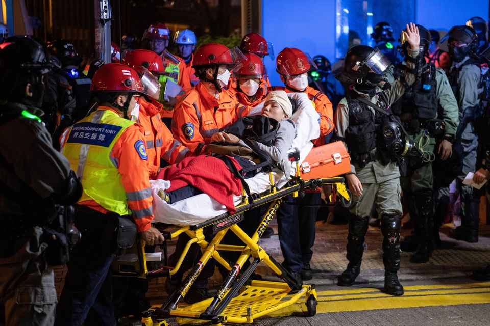 Injured people are taken away after clashes between anti-government protesters and police on Monday