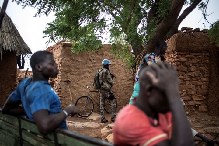 People stand next to a Senegalese soldier of the 2nd Mechanised Company of the Senegalese Battalion of the MINUSMA (United Nations Multidimensional Integrated Stabilisation Mission in Mali) in So on July 4, 2019. (Photo by Marco LONGARI / AFP) (Photo by MARCO LONGARI/AFP via Getty Images)