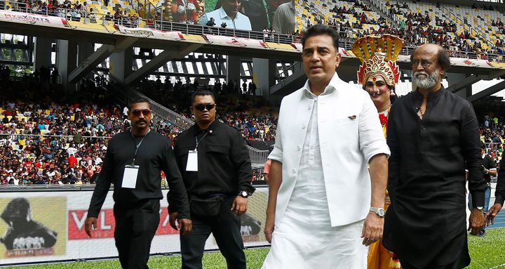 Indian movie superstars Kamal Haasan, center in white, and Rajinikanth, center in black, arrive at an event in Kuala Lumpur, Malaysia, Saturday, Jan. 6, 2018. (AP Photo/Sadiq Asyraf)