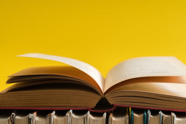 Open book on yellow background, hardback books on wooden table. Education and learning background. Back to school, studying. Copy space for text