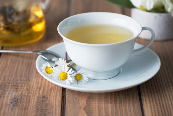 Herbal tea on wooden table with chamomile plants.