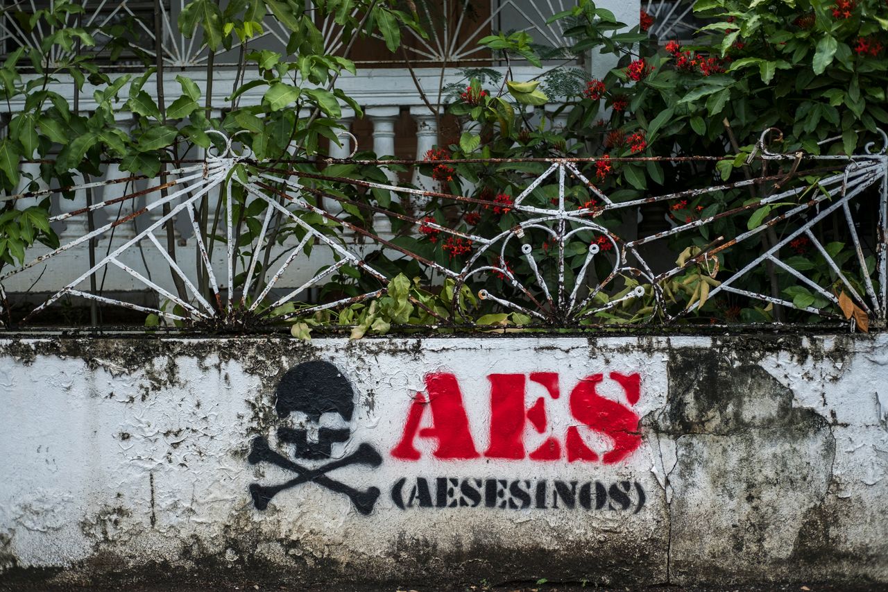 Graffiti reads "AES assassins" at an abandoned house in Guayama.