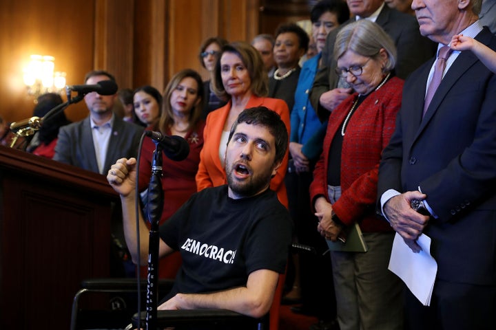 Ady Barkan (center) speaks out against the Republican tax cut bill in December 2017. He is devoting the last years of his life to fighting for his vision of social justice.