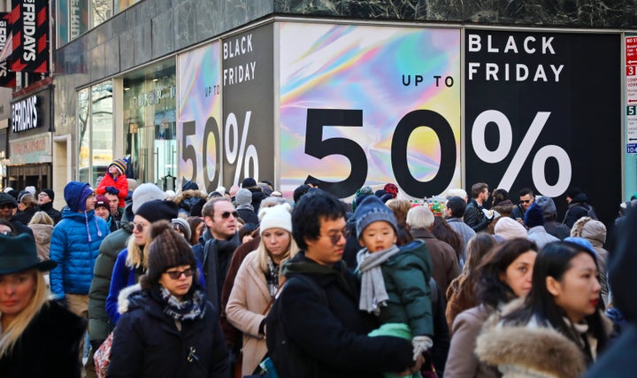 Crowds walk past a large store sign displaying a Black Friday discount in midtown Manhattan, Nov. 23, 2018, in New York City.