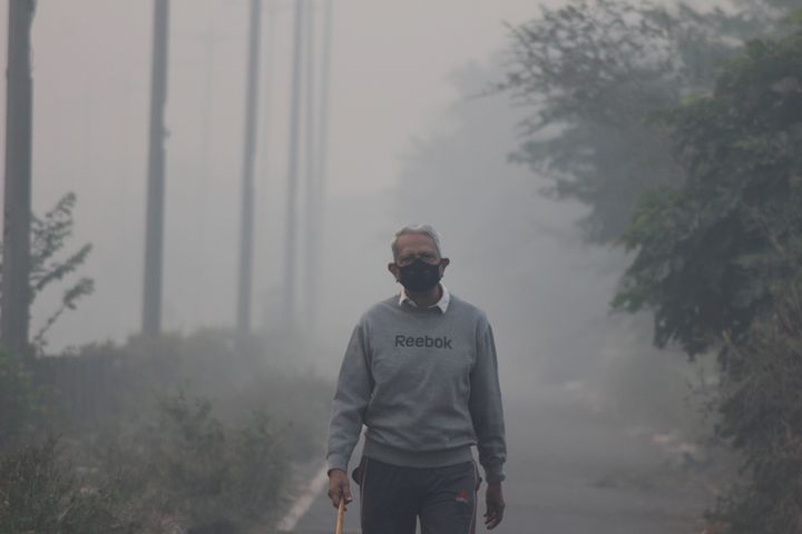 NEW DELHI, INDIA - 2019/11/15: A man wearing a protective mask jogs on a foggy morning in Noida on the outskirts of New Delhi. 