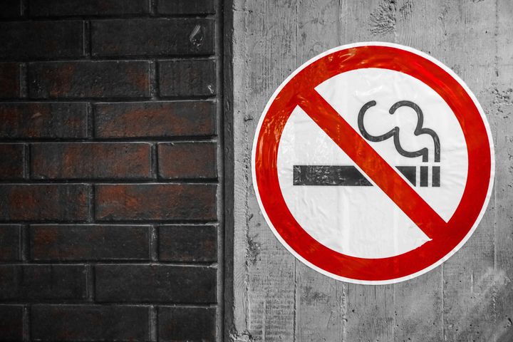 Smoking is not allowed sign on a concrete wall, brick wall on left