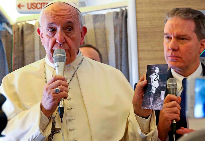 専用機内で「焼き場に立つ少年」のカードを記者団に示すフランシスコ教皇