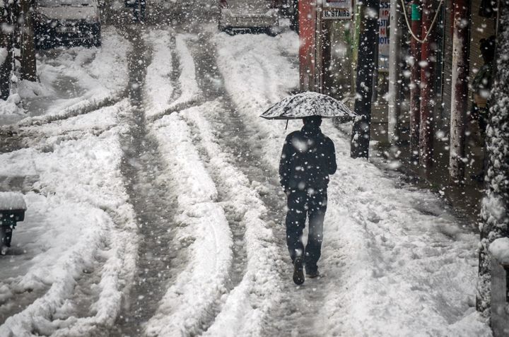 2019/11/09: A resident walks along a snow covered road while holding an umbrella during the heavy snowfall in Kashmir. 