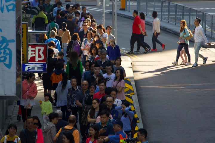 People line up to vote outside of a polling place in Hong Kong, Sunday, Nov. 24, 2019. Long lines formed outside Hong Kong polling stations Sunday in elections that have become a barometer of public support for anti-government protests now in their sixth month. (AP Photo/Ng Han Guan)