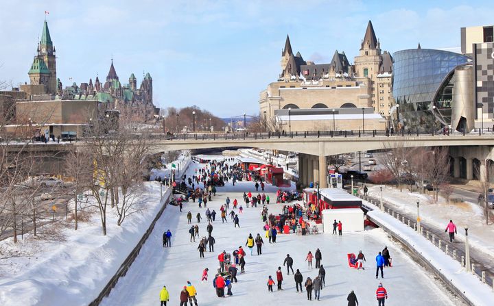 In this stock photo, skaters are seen on the Rideau Canal in downtown Ottawa, with Parliament Hill on the left.