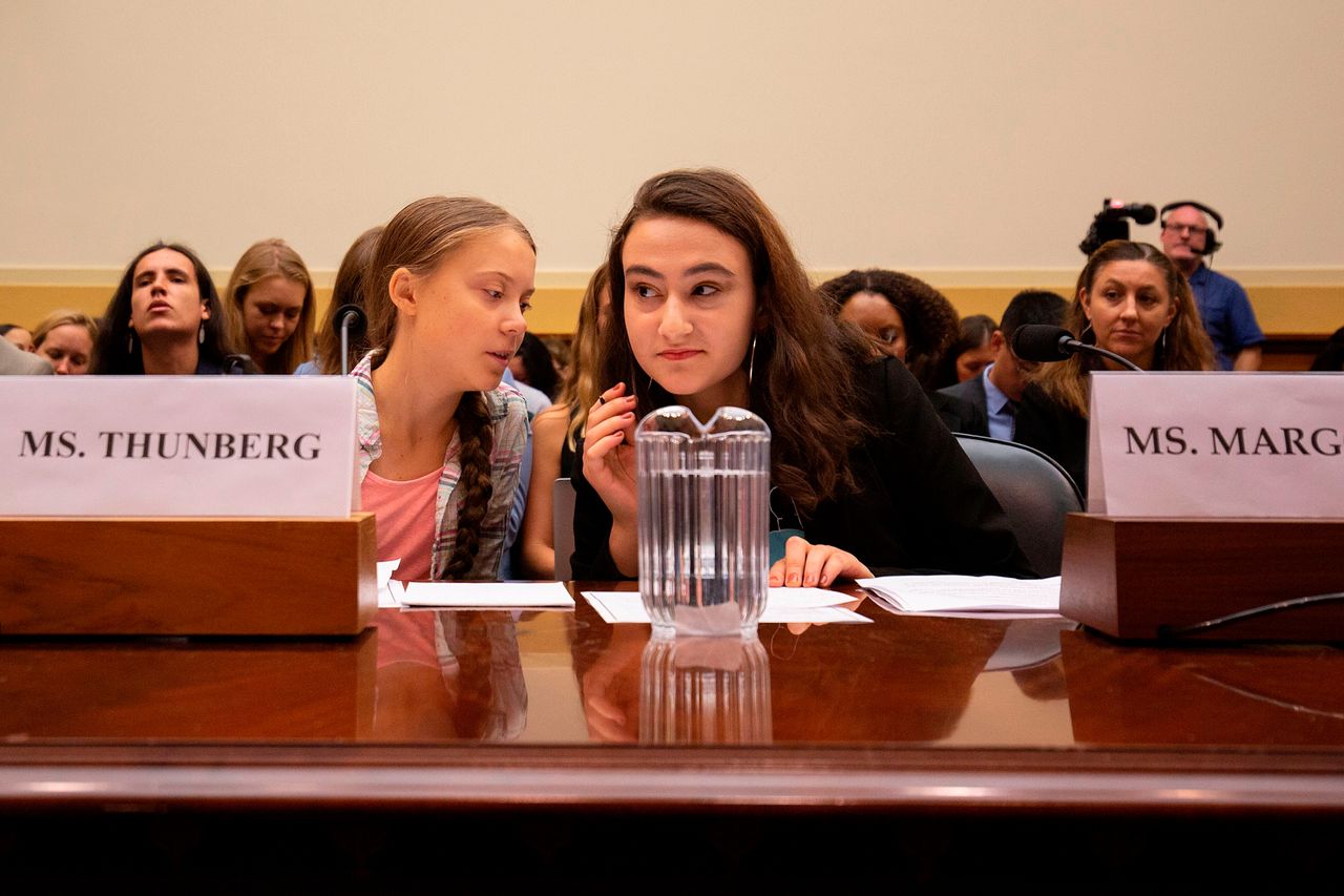 Greta Thunberg, left, talks to Jamie Margolin, right, during a joint hearing before the House Foreign Affairs Committee, Europe, Eurasia, Energy and the Environment Subcommittee, and the House Select Committee on the Climate Crisis on Capitol Hill in Washington, D.C.