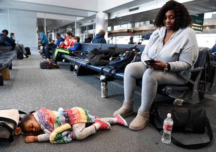 Sonya Washington, right, checks her phone while her granddaughter Nora Lyrse, 2, sleeps comfortably at her feet at the Denver International Airport on Nov. 26, 2019.