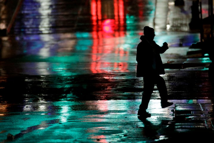 A man is silhouetted as he crosses a rain-covered street on a cold windy night on Nov. 26, 2019, in Kansas City, Mo. The area