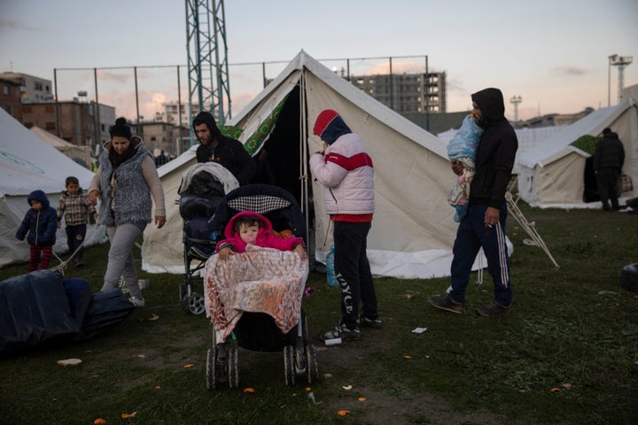 People stand outside a tent at a makeshift camp at a soccer field in Durres, western Albania, on Nov. 27, 2019.