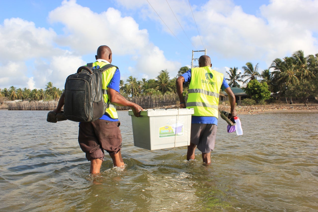 Safari Doctors carry supplies ashore at one of the stops on their route. The group sets up mobile clinics in each village for a few hours before moving on to the next stop. Each night, they camp out under the stars with people from the community.