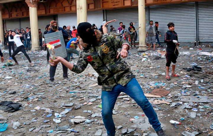 An anti-government protester prepares to throw a molotov cocktail toward security forces during clashes on Rasheed Street in Baghdad, Iraq, on Nov. 28, 2019. 