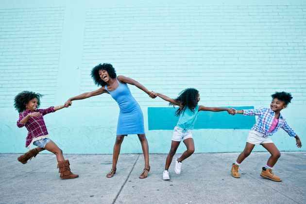 Girls pulling arms of woman in opposite directions