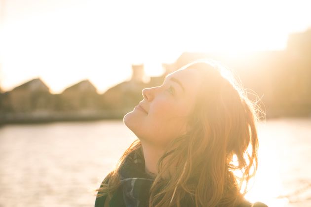 Young woman looking up at the sky next to Gallions Point Marina at Silvertown in East London on a sunny afternoon.