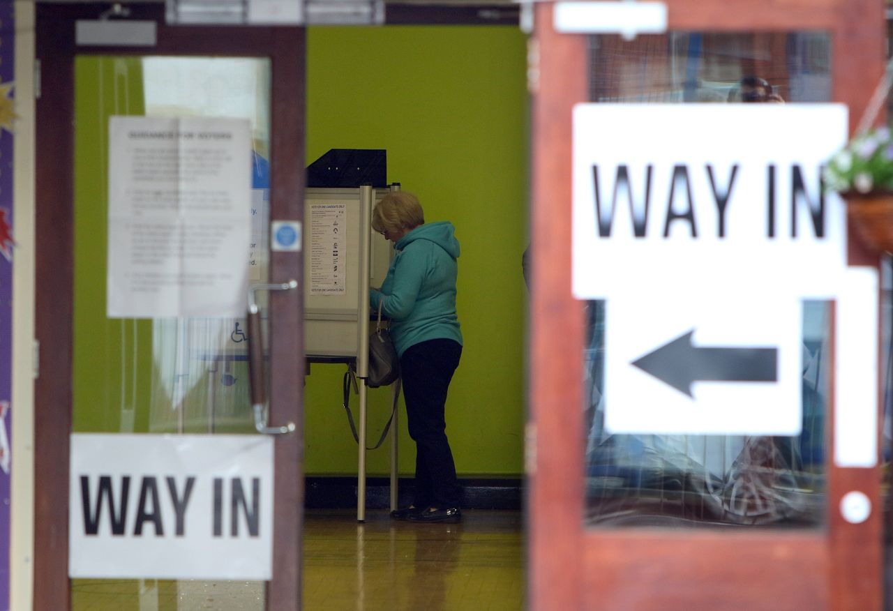 A voter stands at a booth inside a polling station as she prepares to cast her vote in Belfast on May 7, 2015.