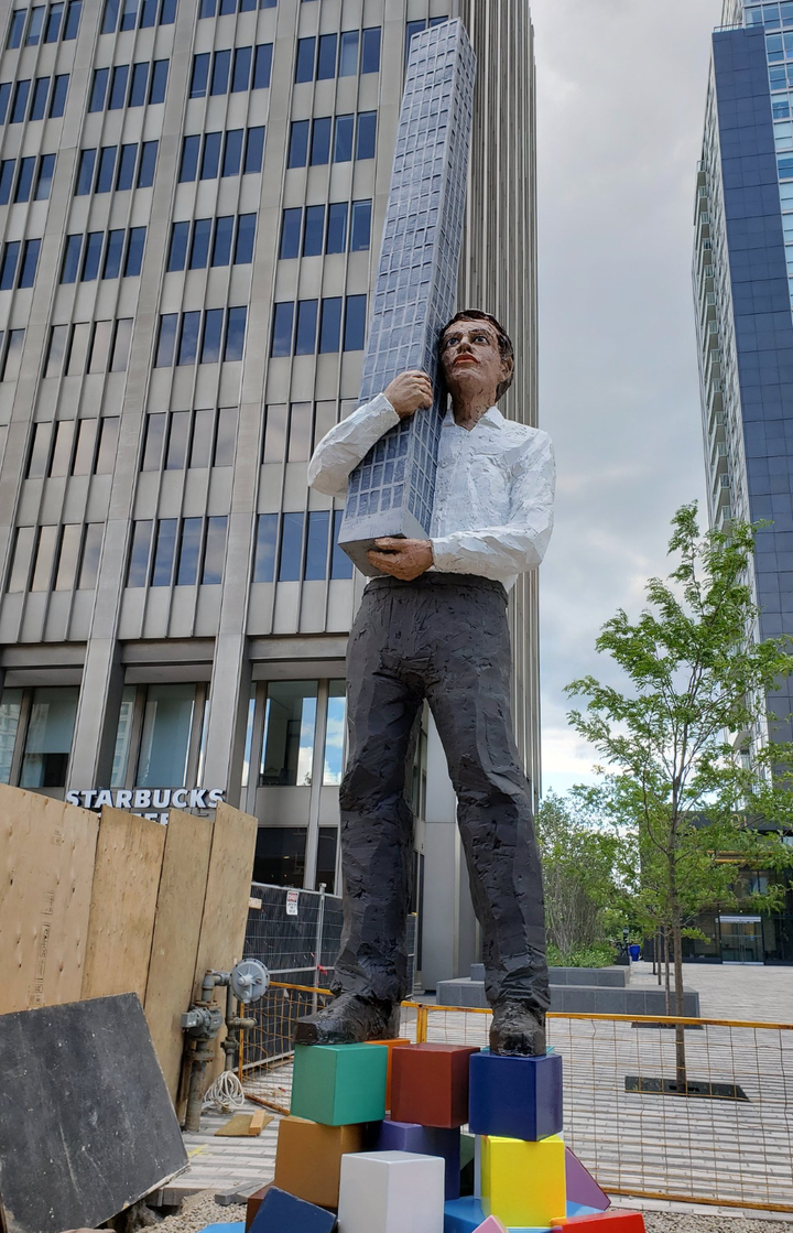 A 25-foot statue of a man holding a condo building outside of a Toronto condo development. 