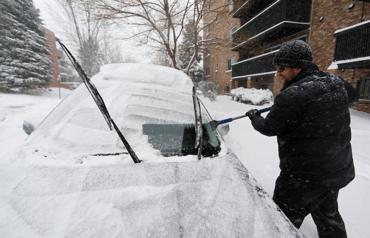 Szymon Lobocki, a rocket engineer from Denver, clears off his Subaru to drive to work in a south suburb as a storm packing sn