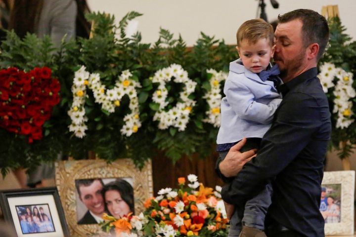 Tyler Johnson, the husband of Christina Marie Langford Johnson, who was killed by unknown assailants in Mexico on Nov. 4, holds a child during her funeral service in LeBaron, Chihuahua, Mexico.